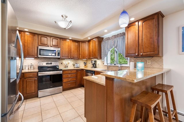 176 Prospect Hill Rd, Colchester, CT 06415 - kitchen with stainless steel appliances, a peninsula, brown cabinets, decorative backsplash, and light stone counters