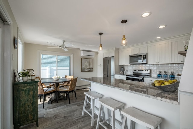 35 Soundview Ave, Old Saybrook, CT 06475 - kitchen with stainless steel appliances, an AC wall unit, a peninsula, a baseboard heating unit, and dark wood-style floors