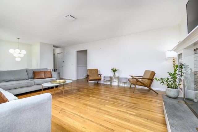 525 Bennetts Farm Rd, Ridgefield, CT 06877 - living room featuring light wood-type flooring, a chandelier, baseboards, and a brick fireplace