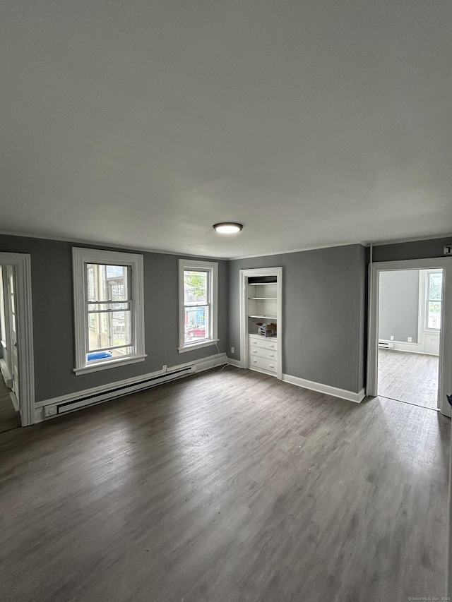 51 Division St, Norwich, CT 06360 - unfurnished living room featuring a baseboard heating unit, wood finished floors, and built in shelves