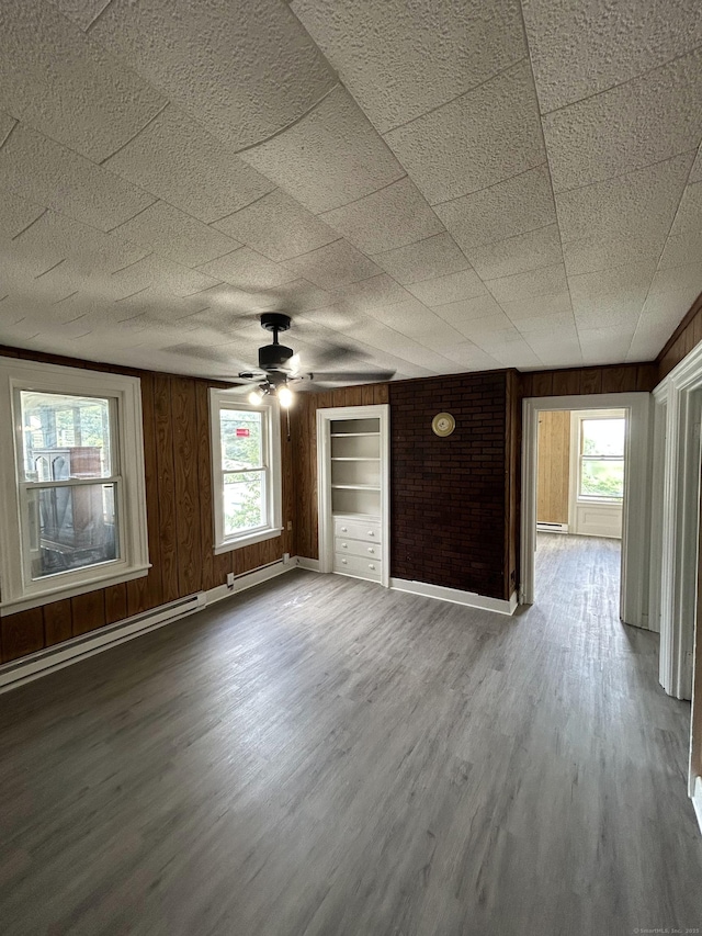 51 Division St, Norwich, CT 06360 - unfurnished living room featuring wood finished floors, ceiling fan, wood walls, and baseboard heating
