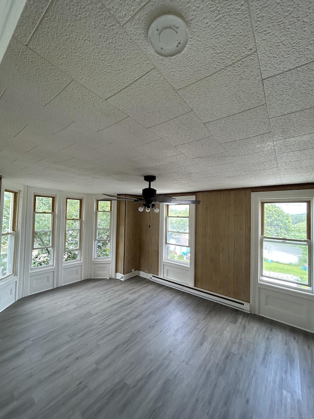51 Division St, Norwich, CT 06360 - empty room with baseboard heating, wood finished floors, a smoke detector, ceiling fan, and wood walls