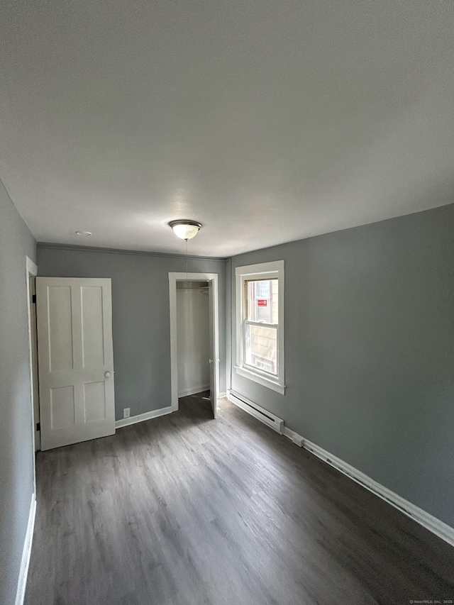 51 Division St, Norwich, CT 06360 - unfurnished bedroom featuring a baseboard heating unit, dark wood finished floors, and a closet