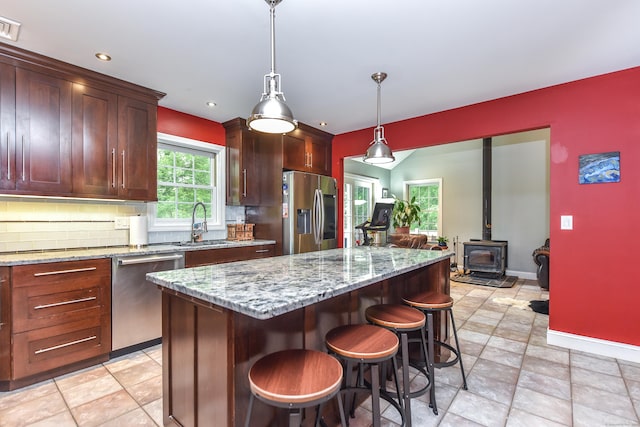10 Heritage Way, Barkhamsted, CT 06063 - kitchen with stainless steel appliances, backsplash, open floor plan, a kitchen bar, and a wood stove