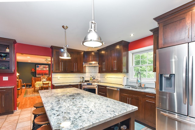 10 Heritage Way, Barkhamsted, CT 06063 - kitchen featuring appliances with stainless steel finishes, under cabinet range hood, tasteful backsplash, light stone counters, and a kitchen island