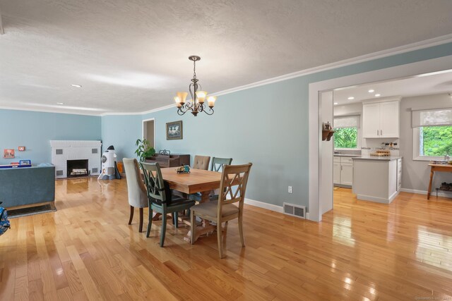 1704 Hill St, Suffield, CT 06078 - dining space with light wood finished floors, a fireplace, a chandelier, crown molding, and recessed lighting