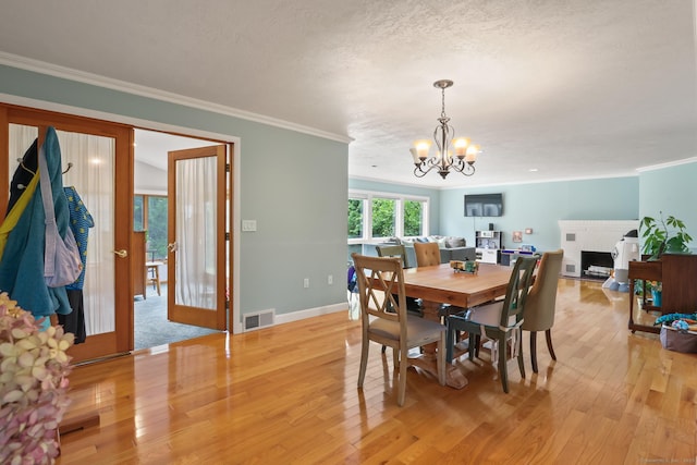 1704 Hill St, Suffield, CT 06078 - dining space featuring a chandelier, light wood-style flooring, ornamental molding, a fireplace, and a textured ceiling
