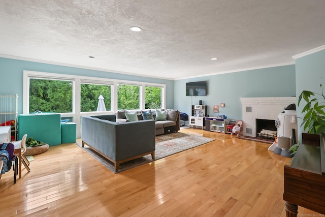 1704 Hill St, Suffield, CT 06078 - living room featuring a textured ceiling, crown molding, light wood-type flooring, and a brick fireplace