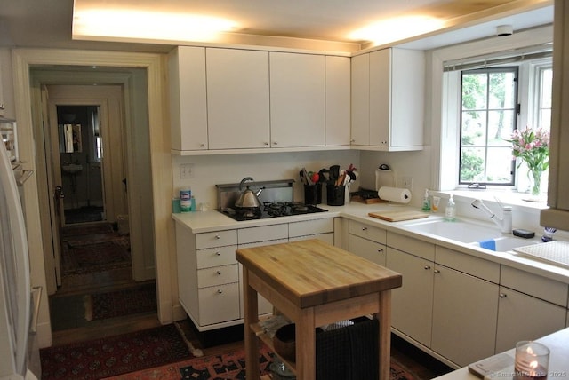 175 Tokeneke Dr, North Haven, CT 06473 - kitchen with black gas stovetop, a sink, wooden counters, and white cabinets