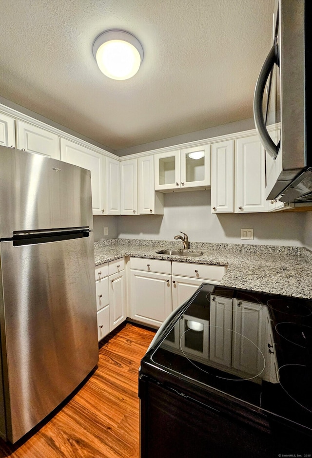 42 Village Rd Unit 42, Southington, CT 06489 - kitchen featuring freestanding refrigerator, black / electric stove, white cabinetry, wood finished floors, and a textured ceiling