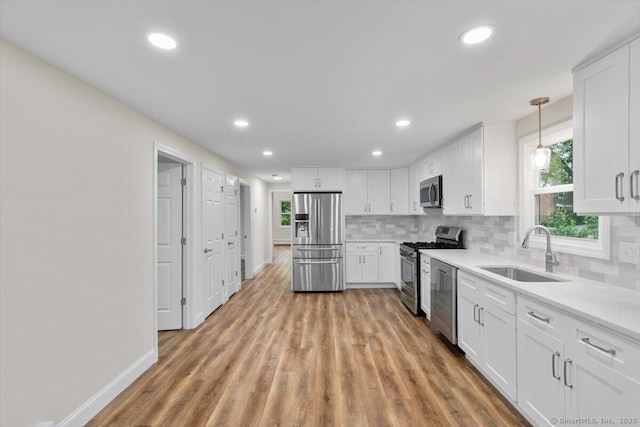 121 Lurton St, New Britain, CT 06053 - kitchen with appliances with stainless steel finishes, a sink, white cabinets, decorative backsplash, and light wood finished floors