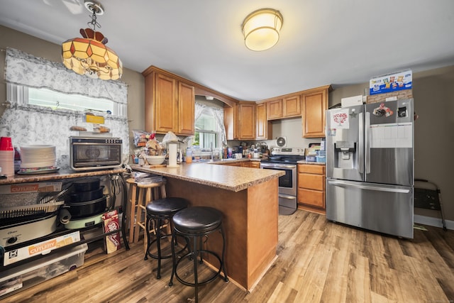 327 Steele St, New Britain, CT 06052 - kitchen featuring stainless steel appliances, light wood-style floors, a peninsula, and brown cabinetry