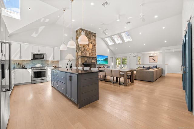 27 Quarry Rd, Stonington, CT 06355 - kitchen featuring stainless steel appliances, a skylight, high vaulted ceiling, open floor plan, and a stone fireplace