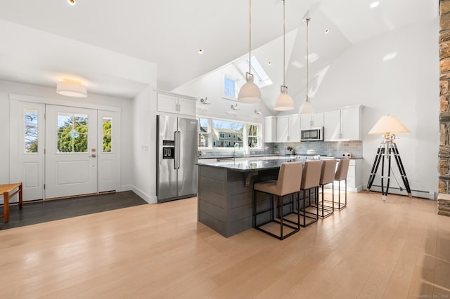 27 Quarry Rd, Stonington, CT 06355 - kitchen featuring appliances with stainless steel finishes, a center island, white cabinetry, a breakfast bar, and high vaulted ceiling