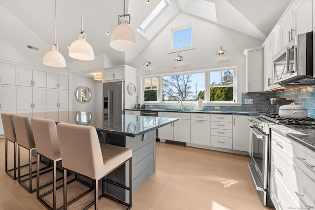 27 Quarry Rd, Stonington, CT 06355 - kitchen featuring stainless steel appliances, a kitchen bar, backsplash, white cabinetry, and a center island