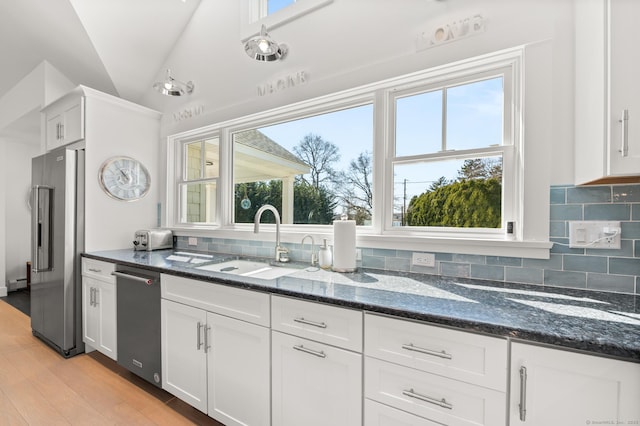27 Quarry Rd, Stonington, CT 06355 - kitchen with stainless steel appliances, a sink, white cabinets, decorative backsplash, and dark stone counters