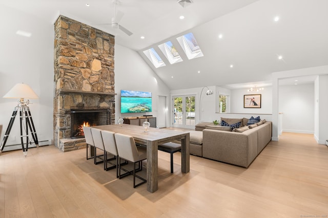 27 Quarry Rd, Stonington, CT 06355 - dining area featuring light wood-type flooring, a fireplace, a baseboard radiator, high vaulted ceiling, and a skylight