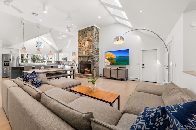 27 Quarry Rd, Stonington, CT 06355 - living room featuring a ceiling fan, high vaulted ceiling, light wood-type flooring, a fireplace, and a skylight