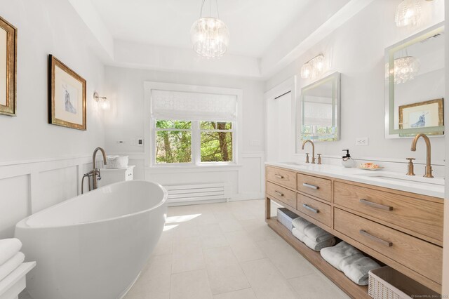 27 Quarry Rd, Stonington, CT 06355 - bathroom with a chandelier, double vanity, wainscoting, a soaking tub, and a decorative wall