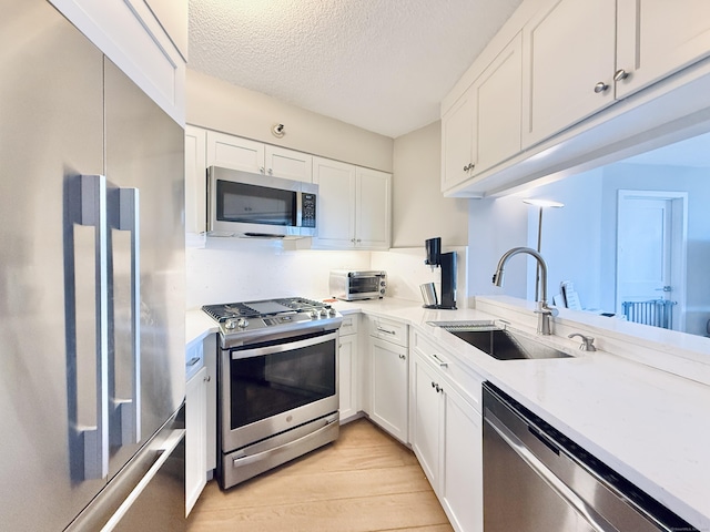 25 Forest St Unit 10B, Stamford, CT 06901 - kitchen with stainless steel appliances, a sink, light wood-style flooring, white cabinets, and a textured ceiling