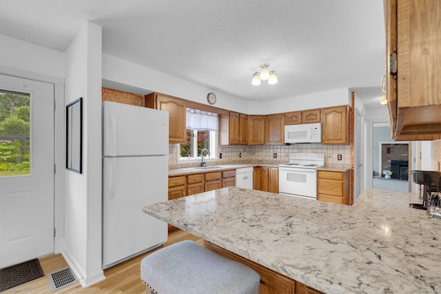 36 Holly Ln, Middletown, CT 06457 - kitchen featuring white appliances, a peninsula, tasteful backsplash, a brick fireplace, and light stone counters