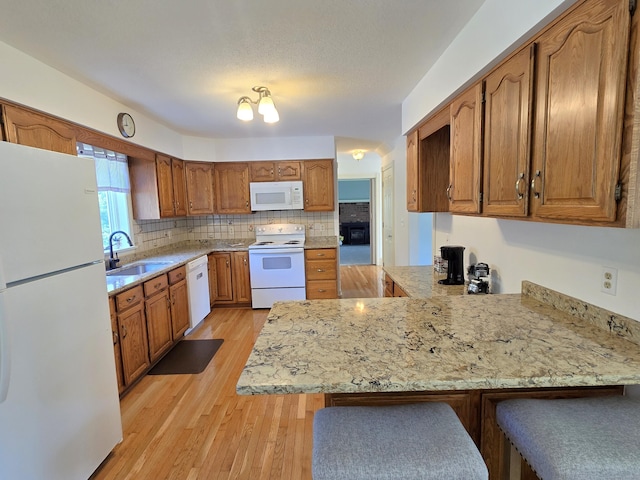 36 Holly Ln, Middletown, CT 06457 - kitchen with white appliances, a peninsula, light wood-style floors, brown cabinetry, and backsplash