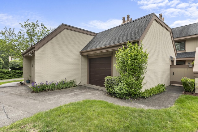85 Viscount Dr Unit 15C, Milford, CT 06460 - view of home's exterior with driveway, brick siding, a garage, a shingled roof, and a chimney