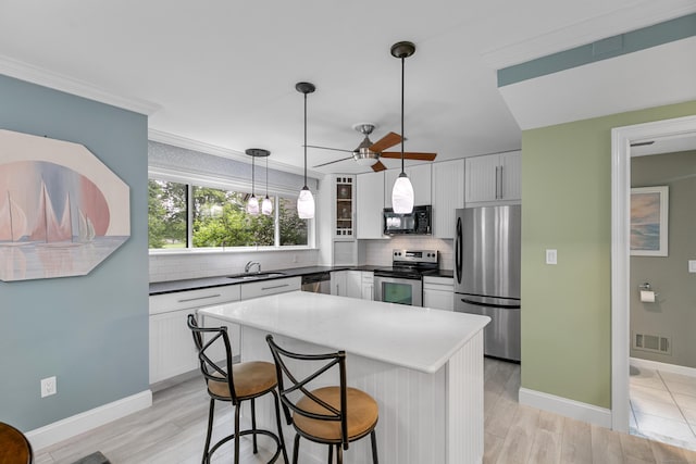 85 Viscount Dr Unit 15C, Milford, CT 06460 - kitchen featuring stainless steel appliances, decorative backsplash, white cabinetry, a ceiling fan, and ornamental molding