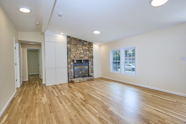 10 Crescent Park Rd, Westport, CT 06880 - unfurnished living room featuring light wood finished floors, a stone fireplace, and lofted ceiling