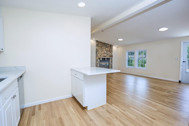 10 Crescent Park Rd, Westport, CT 06880 - kitchen with light wood-style floors, a peninsula, open floor plan, a stone fireplace, and light countertops