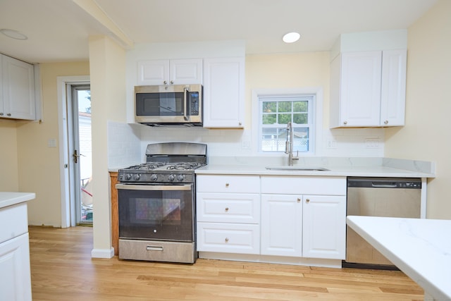 10 Crescent Park Rd, Westport, CT 06880 - kitchen featuring stainless steel appliances, light wood finished floors, decorative backsplash, white cabinets, and light stone counters