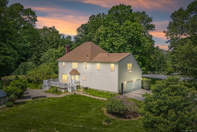 22 Loomis Dr, Coventry, CT 06238 - back of property at dusk with an attached garage, a chimney, driveway, and a yard