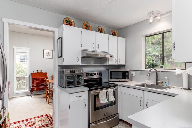 21 Heritage Vlg Unit B, Southbury, CT 06488 - kitchen featuring appliances with stainless steel finishes, a sink, under cabinet range hood, light countertops, and white cabinetry