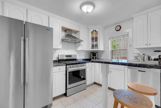 151 Alsace St, Bridgeport, CT 06604 - kitchen with stainless steel appliances, wall chimney exhaust hood, light tile patterned floors, white cabinetry, and glass insert cabinets
