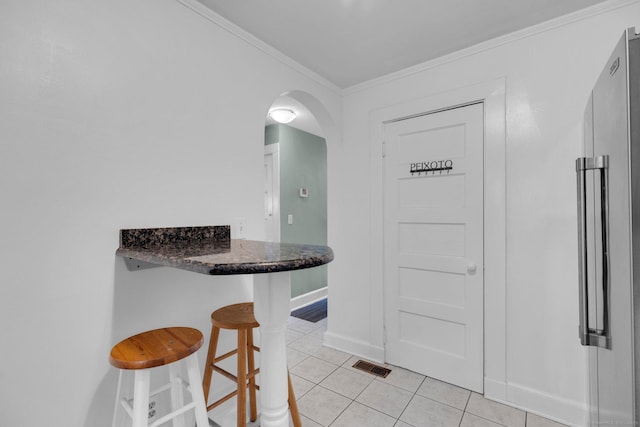 151 Alsace St, Bridgeport, CT 06604 - kitchen featuring a breakfast bar area, light tile patterned floors, baseboards, arched walkways, and crown molding