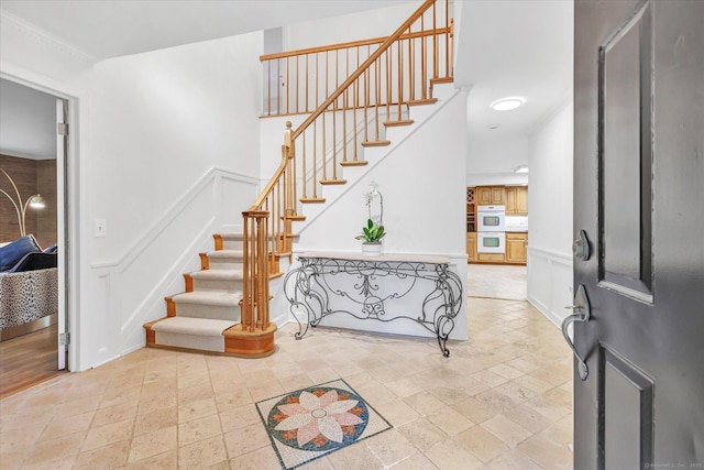 6 Cavray Rd, Norwalk, CT 06855 - entrance foyer featuring stairs, a decorative wall, stone tile flooring, and a wainscoted wall