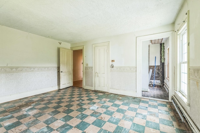 30 Mountain Ave, Winchester, CT 06098 - empty room with a textured ceiling, a wainscoted wall, tile patterned floors, a baseboard radiator, and healthy amount of natural light