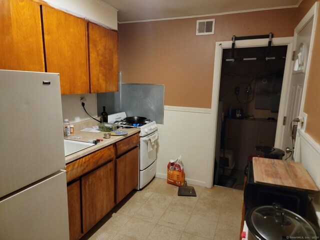 19 Outlook St, East Hartford, CT 06108 - kitchen with white appliances, light countertops, brown cabinets, wainscoting, and crown molding