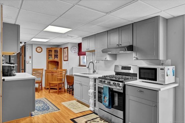 9 Marion Ct, North Haven, CT 06473 - kitchen with stainless steel gas stove, white microwave, gray cabinetry, under cabinet range hood, and a paneled ceiling