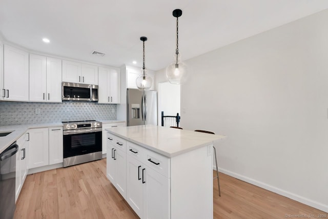 29 Magellan Dr, Milford, CT 06460 - kitchen with stainless steel appliances, light wood finished floors, decorative backsplash, a breakfast bar area, and recessed lighting