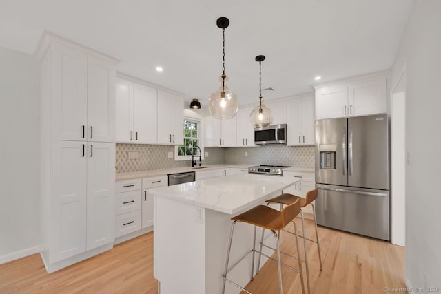 29 Magellan Dr, Milford, CT 06460 - kitchen featuring appliances with stainless steel finishes, light wood-style floors, tasteful backsplash, recessed lighting, and a kitchen island