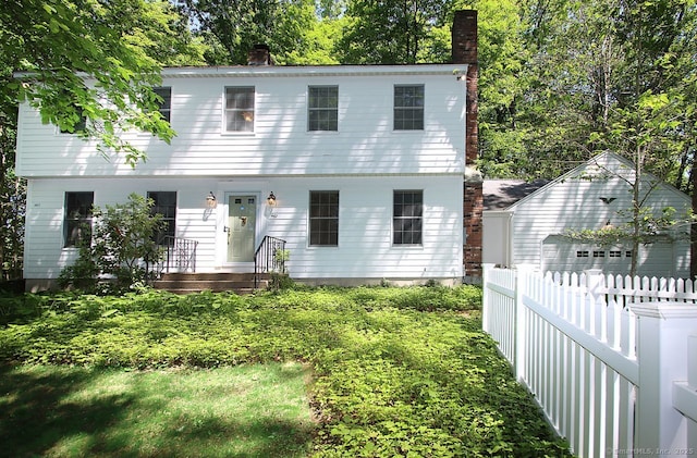 467 Weekeepeemee Rd, Woodbury, CT 06798 - colonial-style house featuring a chimney, a detached garage, view of wooded area, and an outbuilding