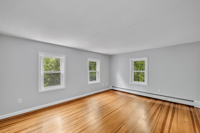 15 Indian Hill Rd, Canton, CT 06019 - unfurnished room featuring hardwood / wood-style flooring, healthy amount of natural light, a baseboard heating unit, a textured ceiling, and baseboards
