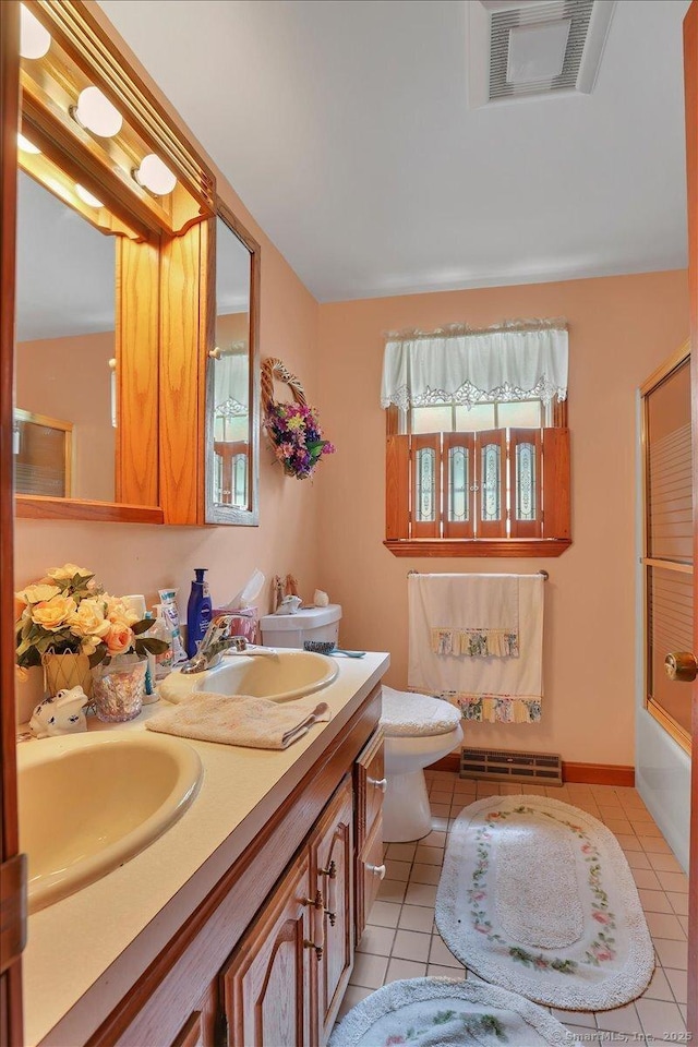 79 Carriage Dr E, Meriden, CT 06450 - bathroom featuring toilet, tile patterned floors, double vanity, and combined bath / shower with glass door