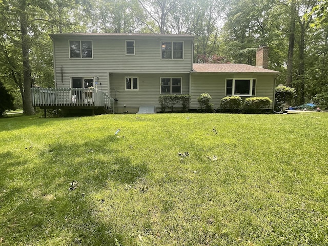 rear view of property with a wooden deck, a chimney, a lawn, and view of scattered trees