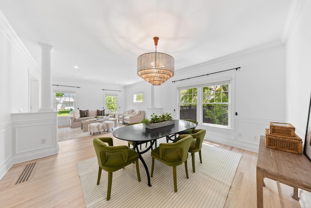 31 Pleasant St, Darien, CT 06820 - dining space featuring decorative columns, crown molding, light wood finished floors, a wainscoted wall, and a decorative wall