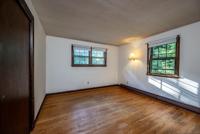 58 Wildwood Ln, Durham, CT 06422 - unfurnished room with a baseboard radiator, plenty of natural light, wood finished floors, a textured ceiling, and baseboards