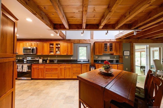 1900 Home Rd, Great Barrington, MA 01230 - kitchen with stainless steel appliances, brown cabinets, wood ceiling with exposed beams, glass insert cabinets, and dark countertops