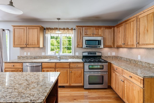2 Acorn Dr, East Haddam, CT 06423 - kitchen featuring appliances with stainless steel finishes, a sink, light stone counters, light wood-type flooring, and pendant lighting