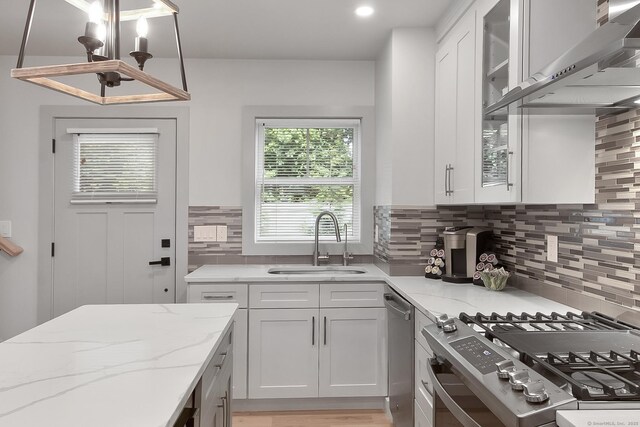 1 Howard Ave Unit C2, Norwalk, CT 06855 - kitchen featuring stove, a sink, wall chimney range hood, white cabinetry, and light stone counters